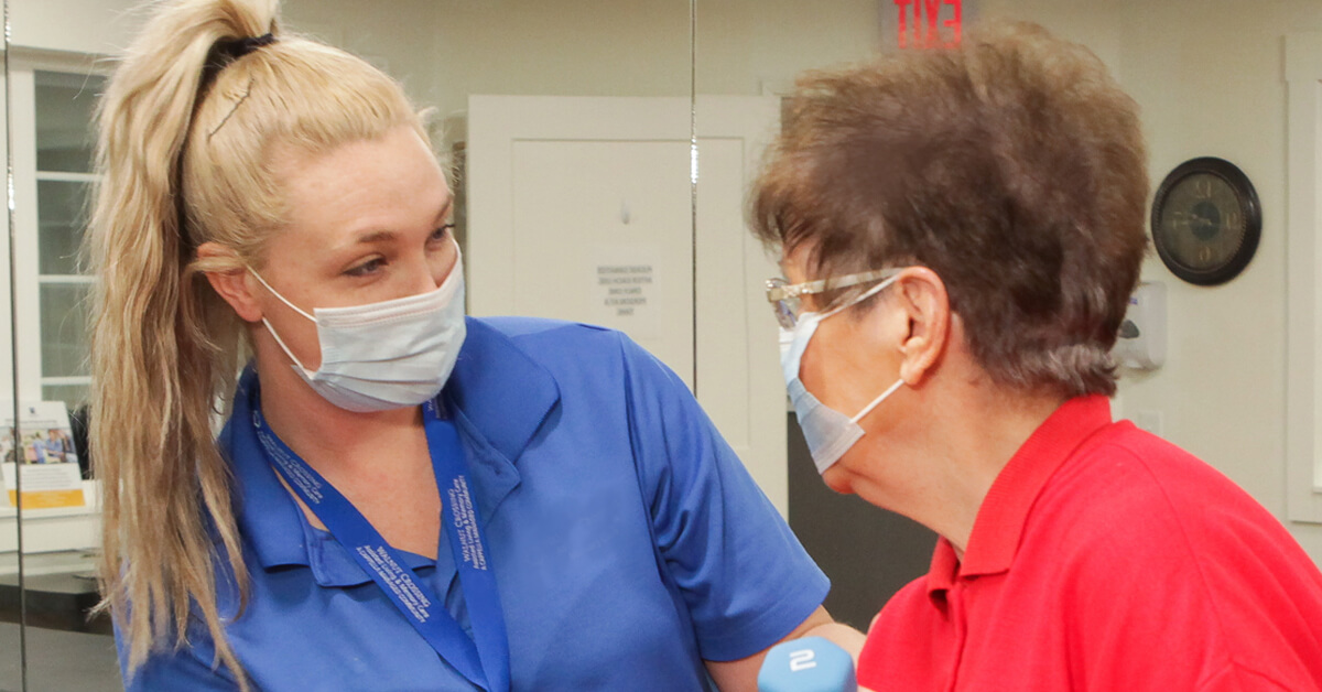 Resident and team member share a smile behind masks.