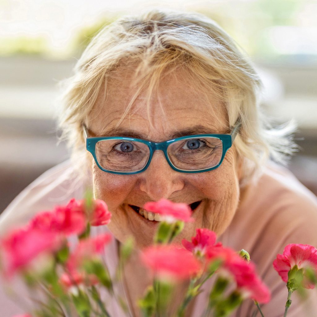 Someren Glen Senior Living Community in Centennial, CO - sg senior woman peering over flowers
