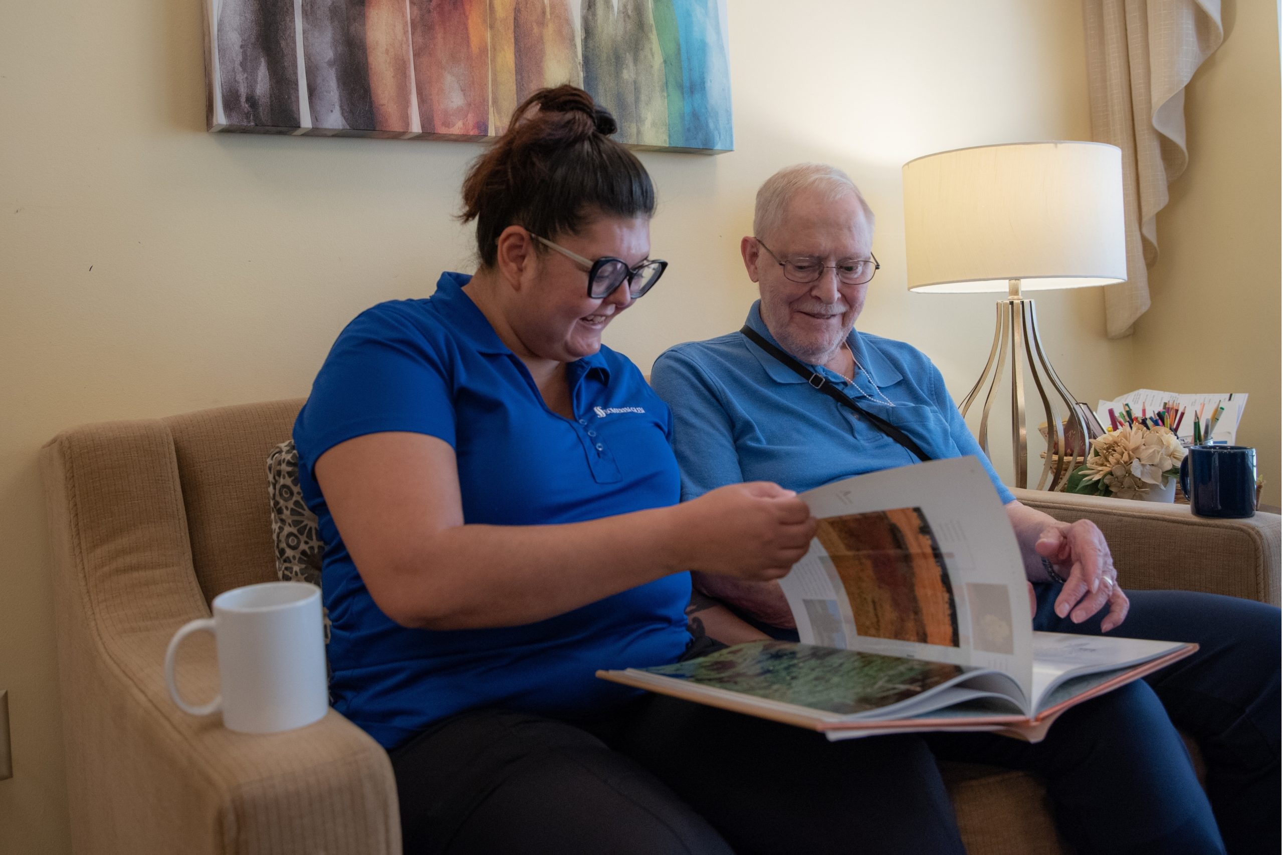 Someren Glen Senior Living Community in Centennial, CO - team member and older resident looking at book largelandscape