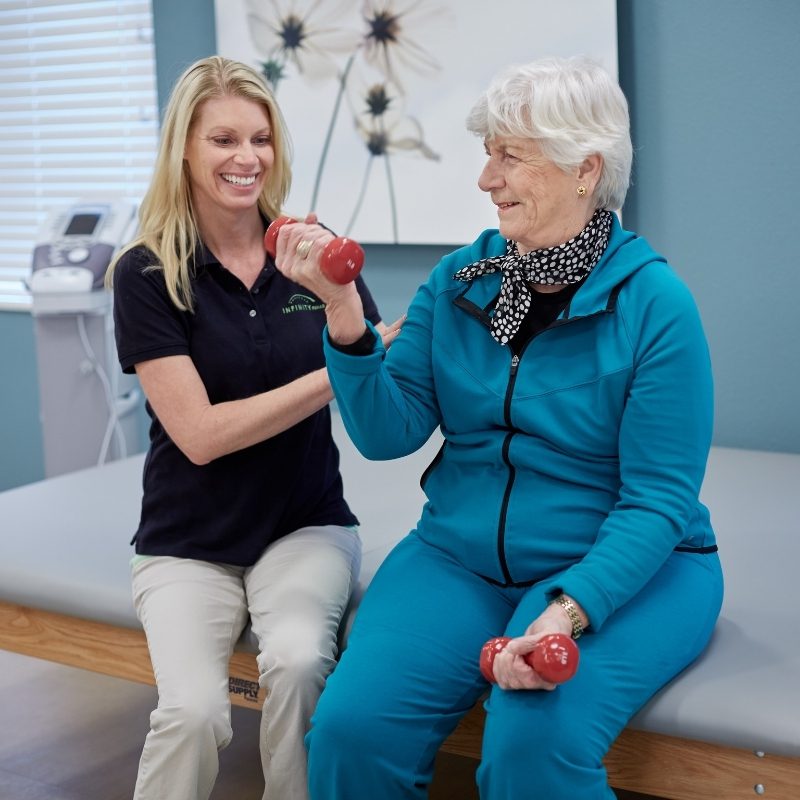 Someren Glen Senior Living Community in Centennial, CO - rehab team member guiding older woman in lifting weights square