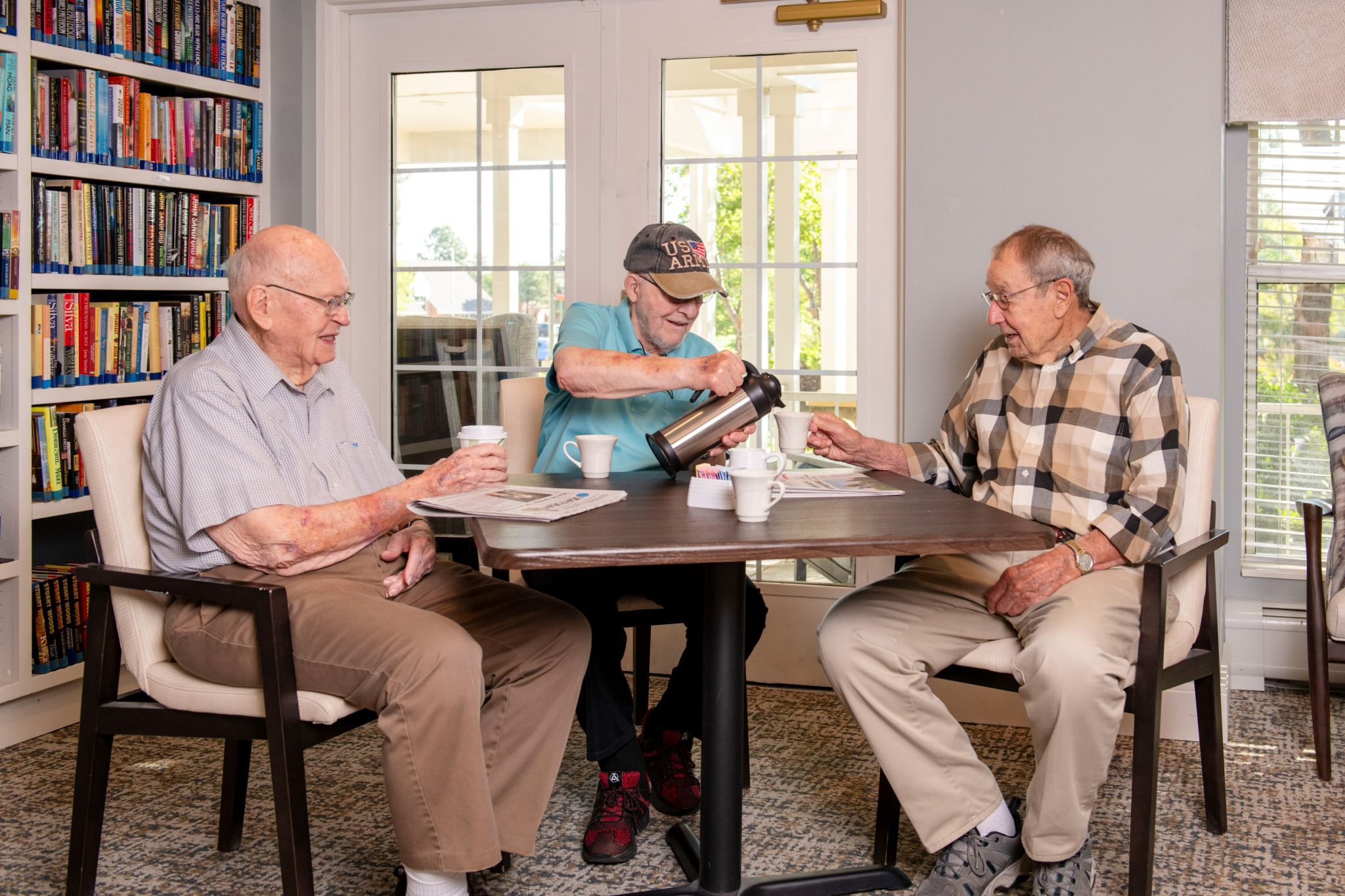 Someren Glen Senior Living Community in Centennial, CO - three older men talking over coffee in library largelandscape