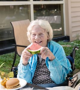 Someren Glen Senior Living Community in Centennial, CO - a woman enjoying a watermelon slice while eating lunch